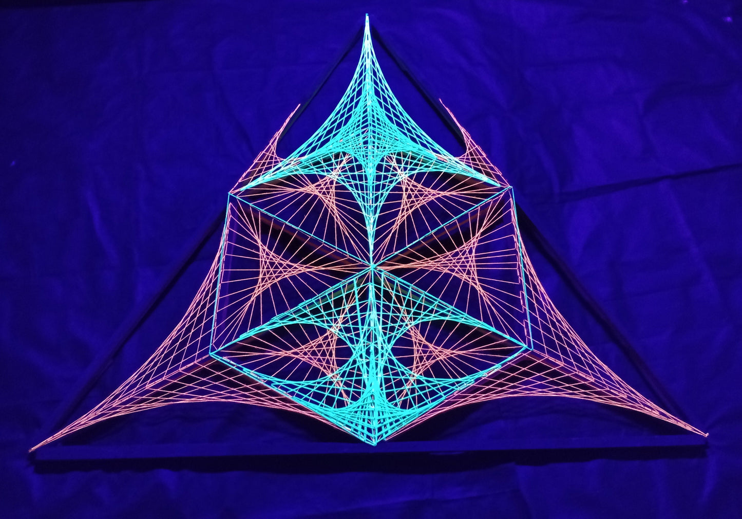 Front view of UV reactive geometric string art installation by Psybell glowing under purple UV lighting