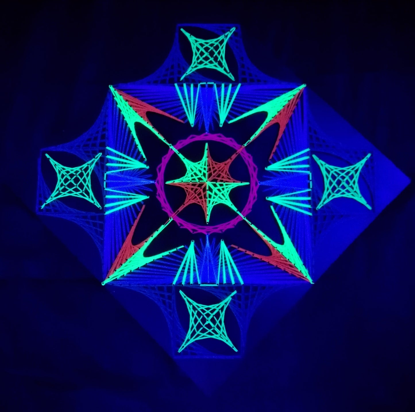 handmade UV reactive geometric string art with symmetrical abstract machine pattern, neon blue, green and red threads, glowing under ultraviolet light, by Psybell
