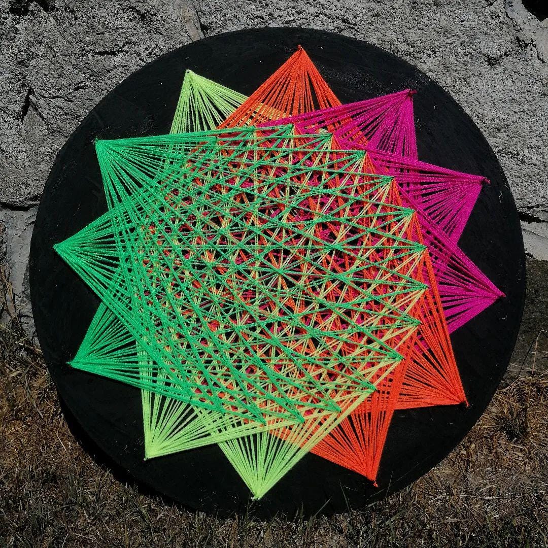 handmade string art circle with symmetrical geometric pattern, rainbow colors design, made from synthetic acrylic threads on MDF wood board, by Psybell
