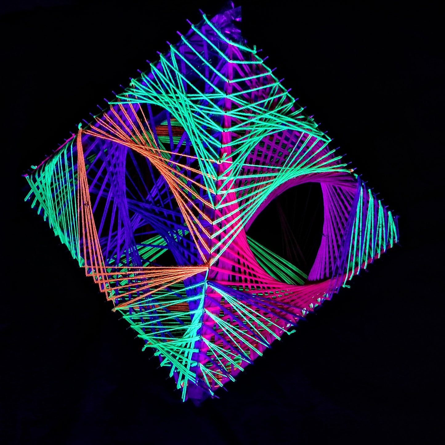 Handmade 3D string art Dragon’s Pyramid under UV light, geometric pyramid sculpture with neon green, purple and orange threads, Psybell