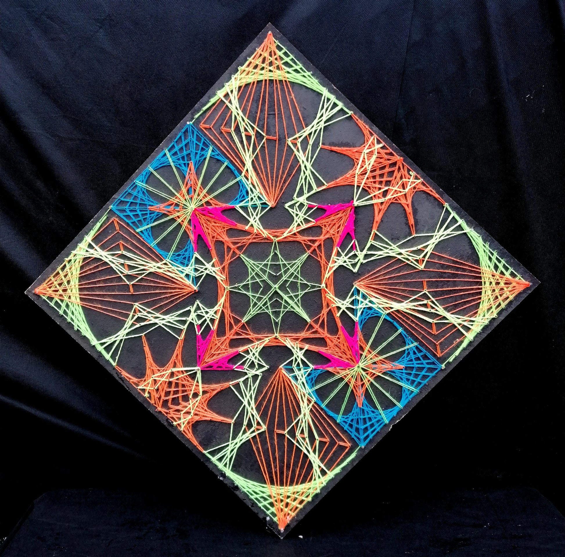 handmade geometric string art with symmetrical electra pattern, neon green, orange, blue and pink threads on black background, precise angular composition, by Psybell