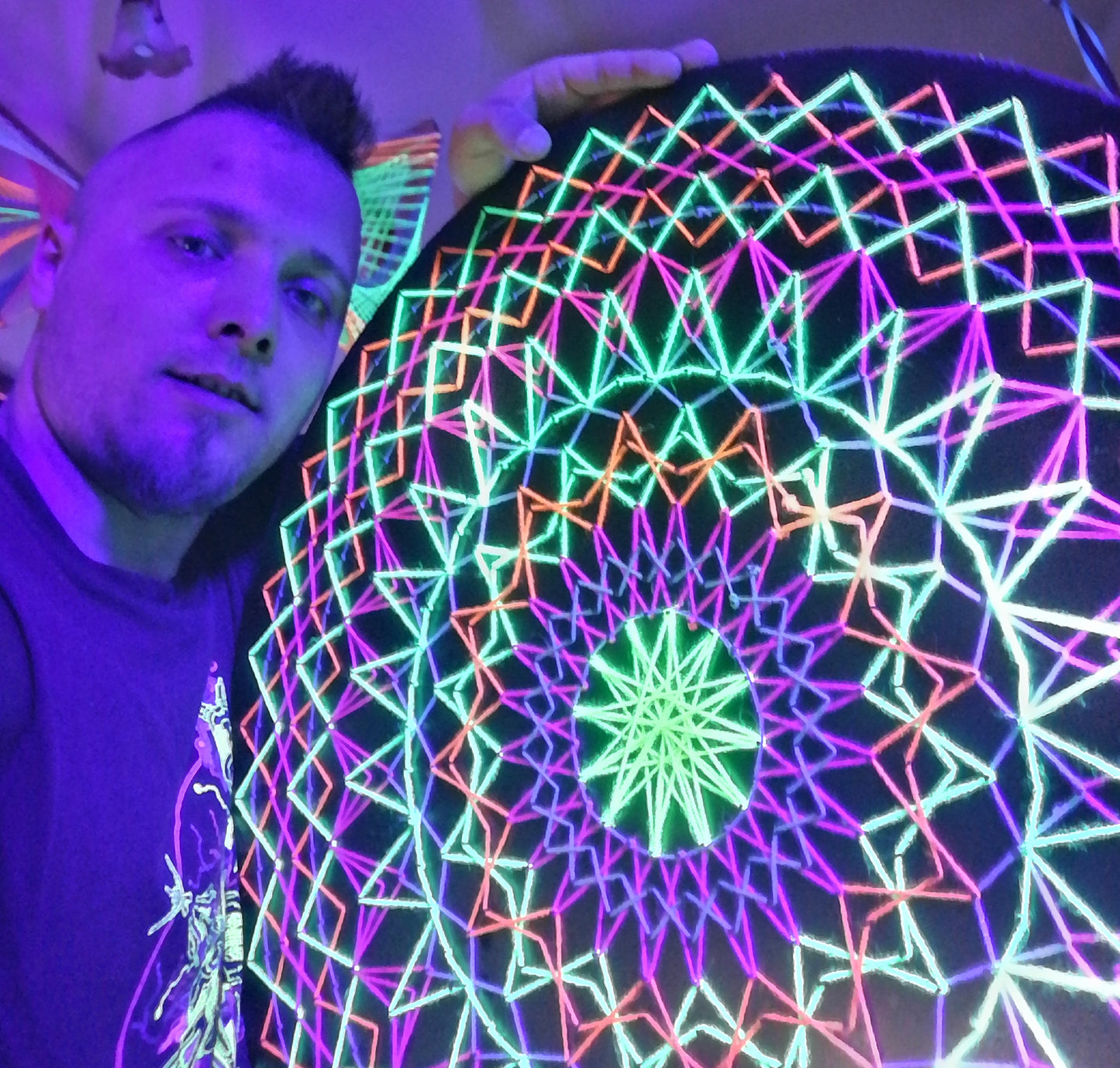 handmade UV reactive string art mandala with symmetrical circular geometry, neon colors, made from cotton threads, by Psybell