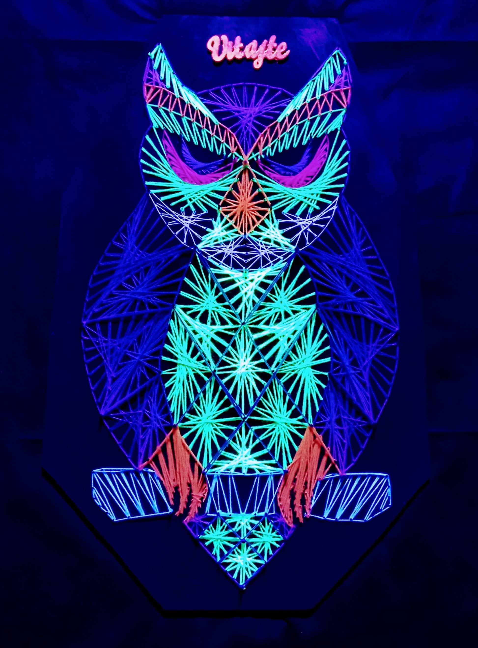 handmade geometric owl string art with symmetrical pattern, colorful UV reactive threads on black background, modern wall art, Psybell