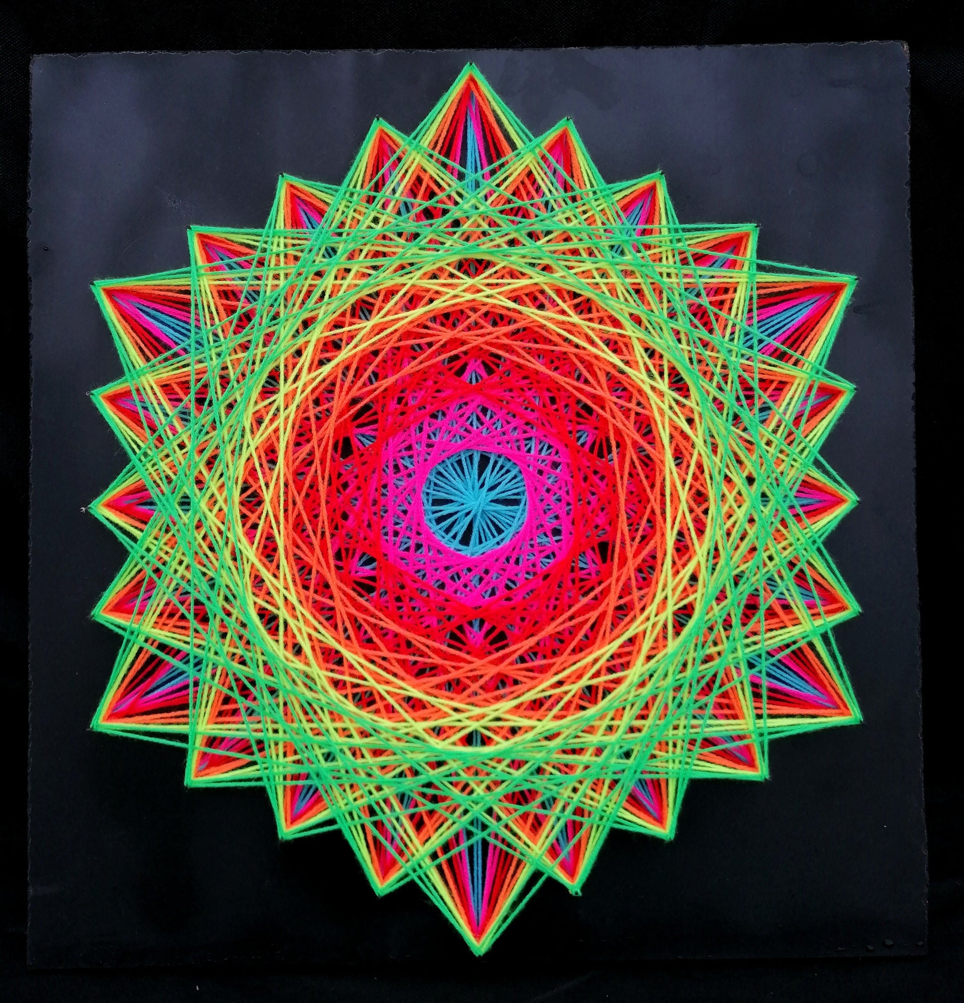 handmade geometric string art with symmetrical hexagon mandala pattern, rainbow multicolor threads on dark background, by Psybell
