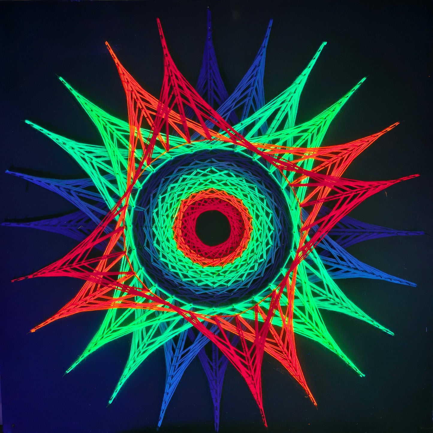 handmade UV reactive square string art with symmetrical spiral vortex pattern, rainbow neon threads, glowing under ultraviolet light, by Psybell
