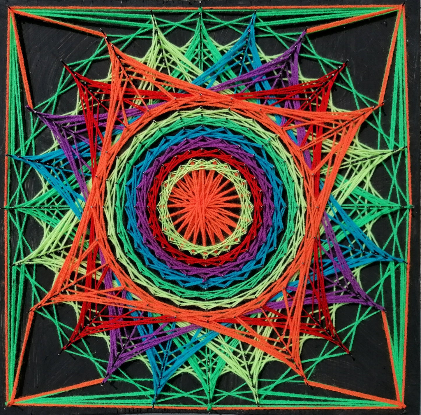 handmade UV reactive square string art with symmetrical spiral mandala pattern, multicolor neon threads, glowing under ultraviolet light, by Psybell
