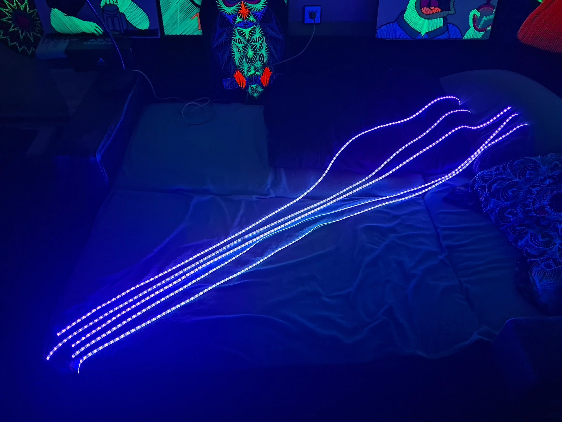 UV LED light sculpture on a dark surface with colorful abstract art in the background