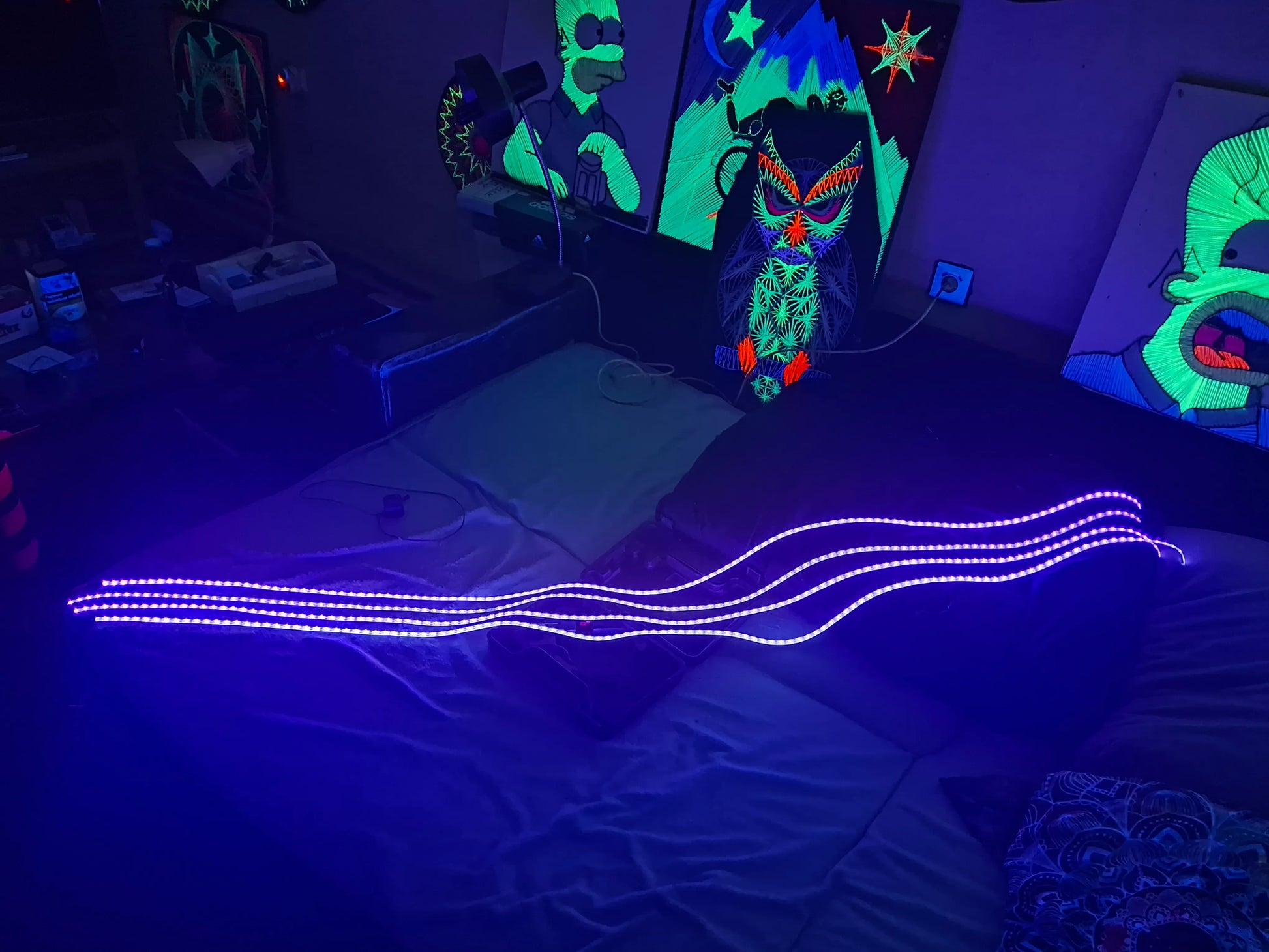 Neon lights on a bed with a colorful mask and string arts in the background