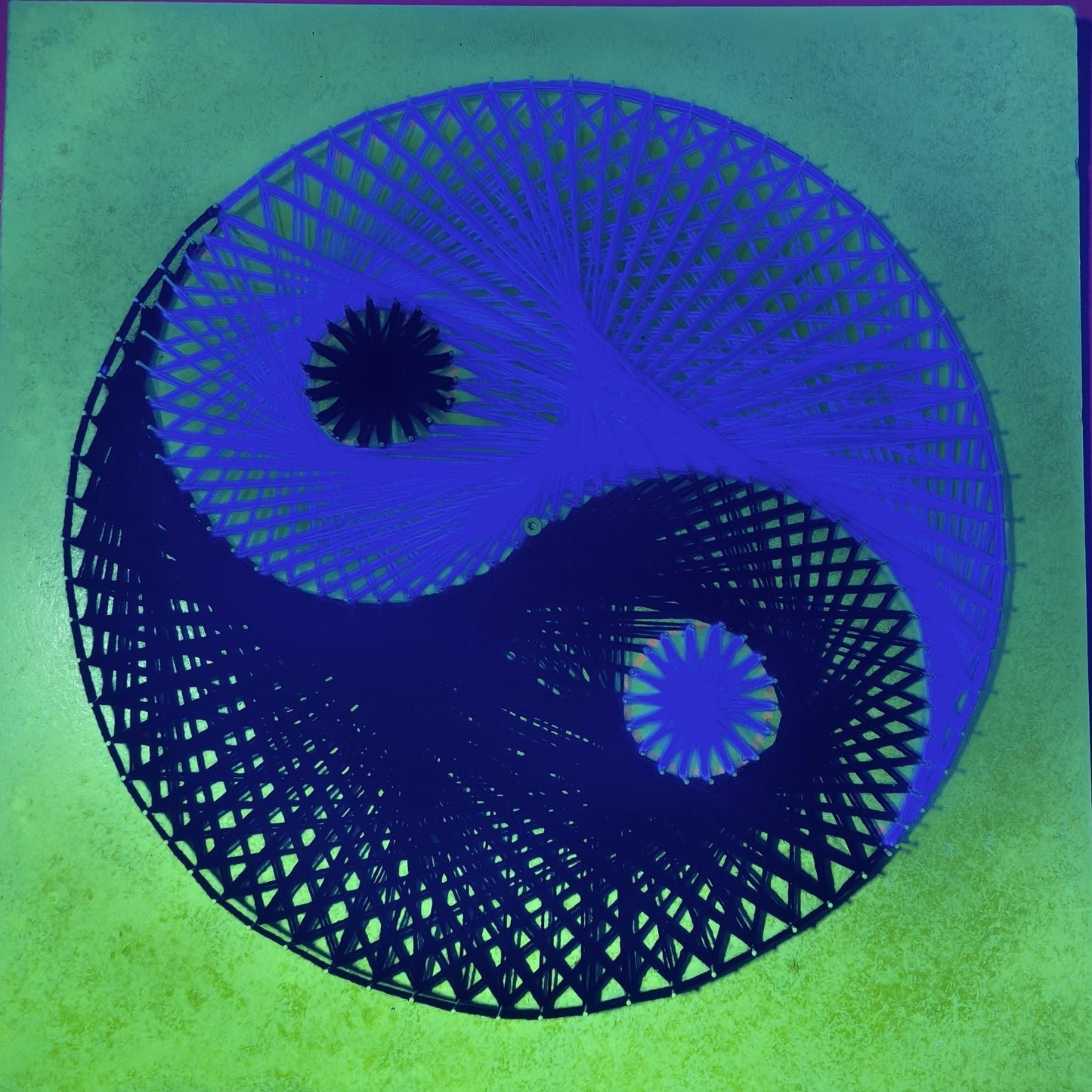 Yin and Yang UV string art displayed in modern interior glowing under blacklight
