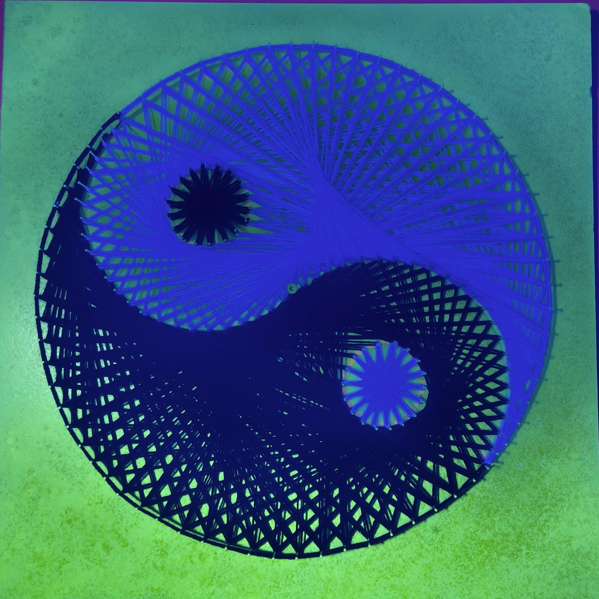 Yin and Yang UV string art displayed in modern interior glowing under blacklight
