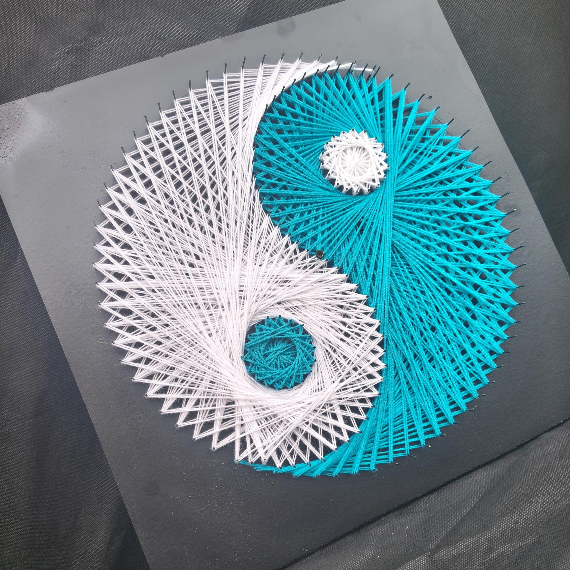 Side view of handmade Yin and Yang string art showing layered geometric thread structure