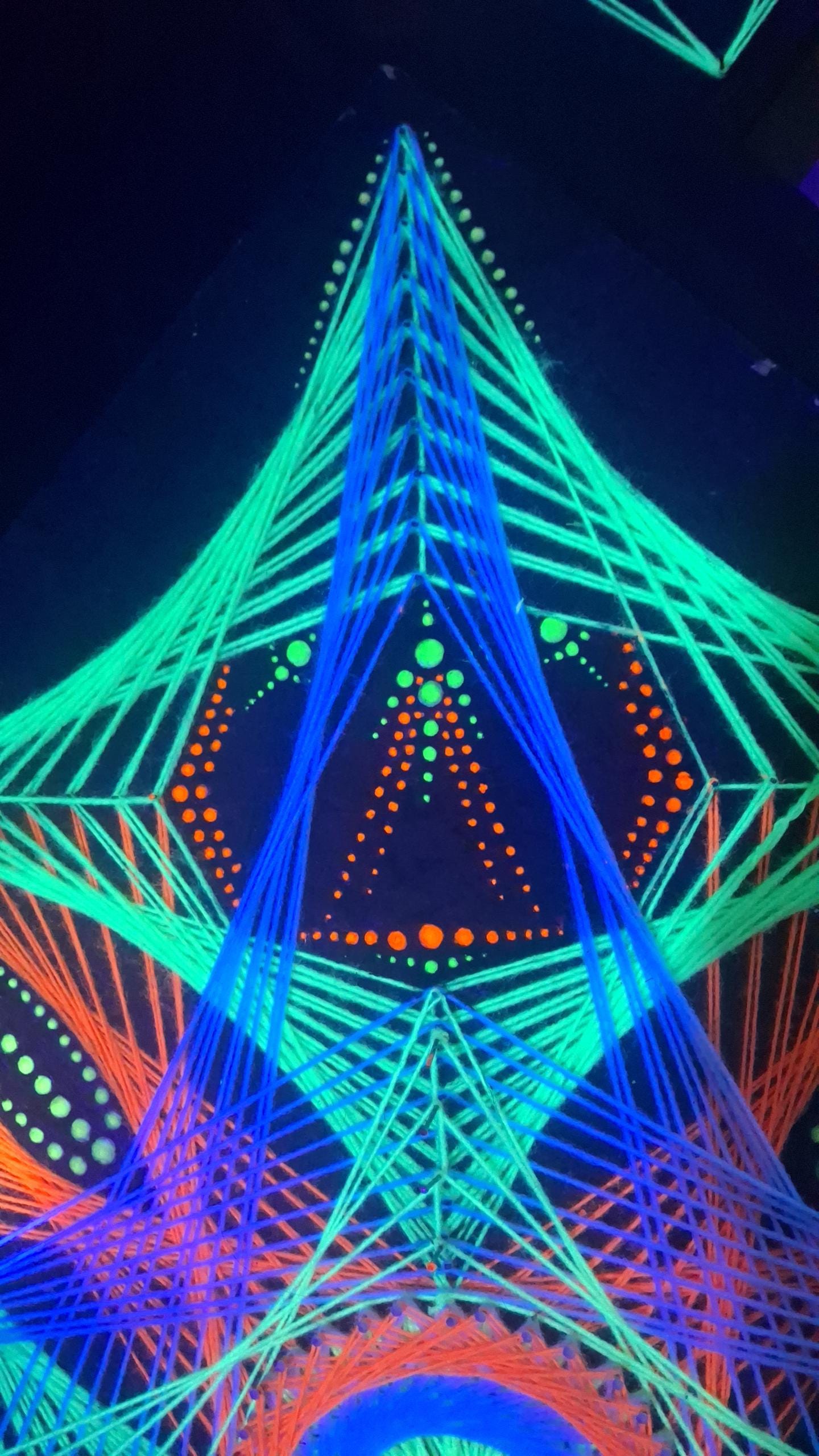 detail of UV reactive dotted mandala in handmade string art “Aura Flow”, close-up view showing nail placement, glowing dots and thread geometry under ultraviolet light