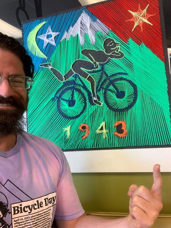 string art Hoffman trip artwork on wooden board displayed with its owner featuring colorful thread design inspired by Bicycle Day 1943 by Psybell