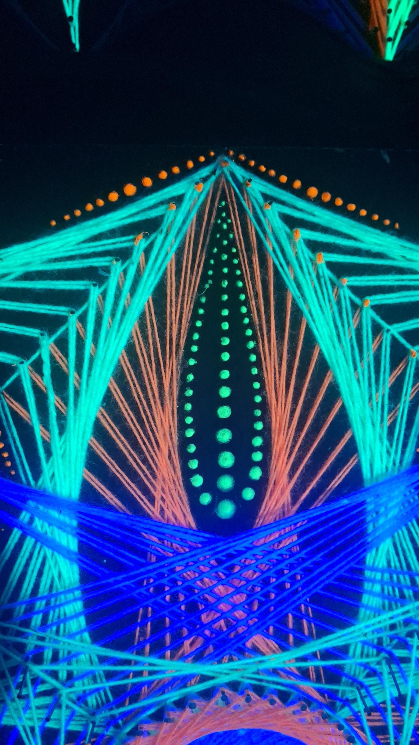 detail of UV reactive dotted mandala in handmade string art “Aura Flow”, close-up view showing nail placement, glowing dots and thread geometry under ultraviolet light