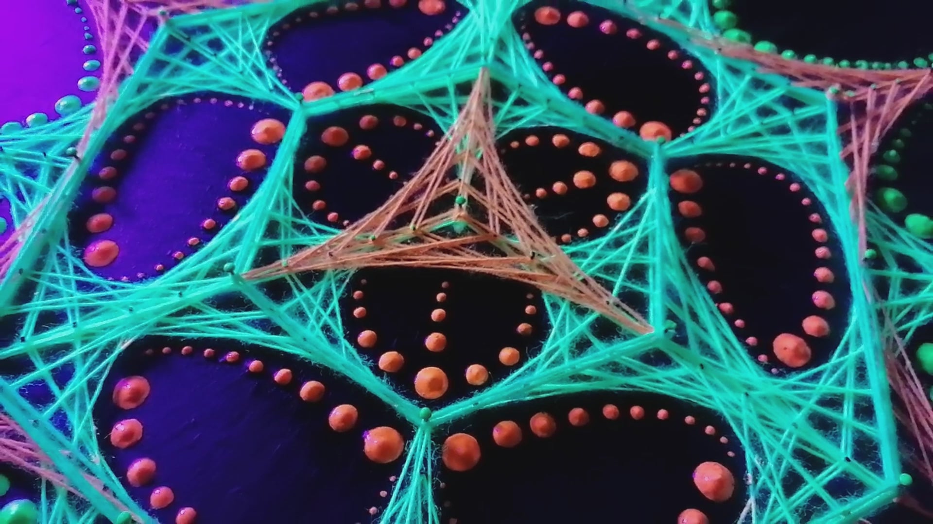 UV glow macro video of dotted mandala string art “Transformer” by Psybell under blacklight showing colorful thread geometry