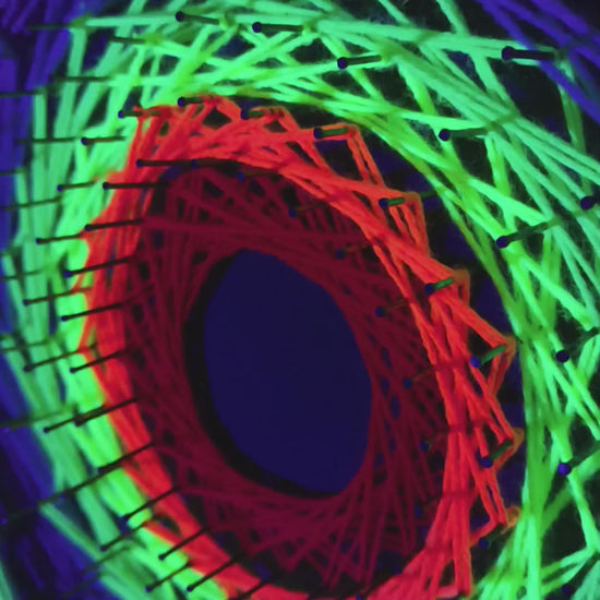 Video of Rainbow Singularity handmade UV string art wall decor glowing under ultraviolet light – detailed geometry and neon colors