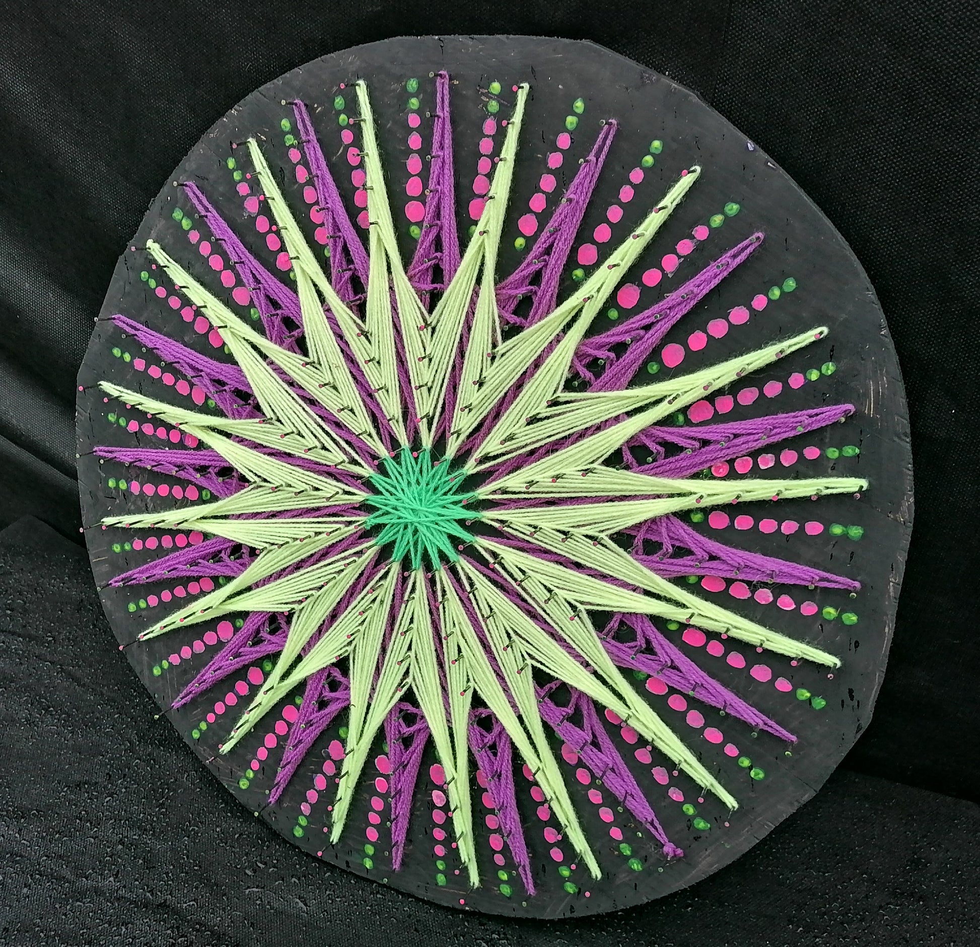 Geometric string art mandala “Aura Flow” by Psybell showing fluorescent threads and dotted jellyfish pattern on round wooden board