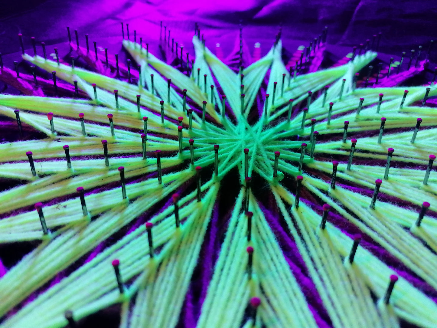 Extreme macro detail of geometric string art “Aura Flow” by Psybell showing fluorescent threads wrapped around nails forming jellyfish pattern