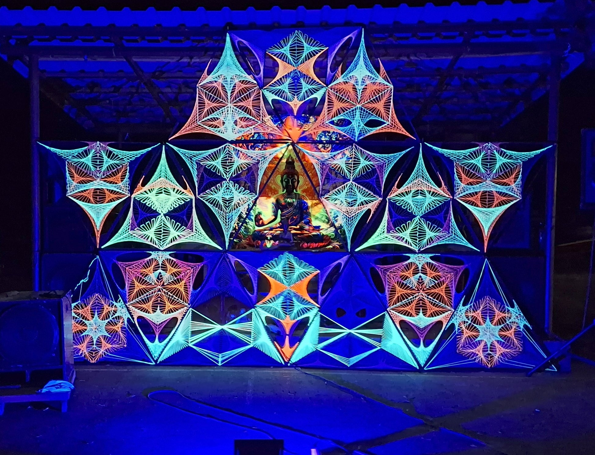 Large UV reactive string art stage installation by Psybell at Full Moon Festival in Drahovce Slovakia, psychedelic geometric decor glowing under blacklight.
