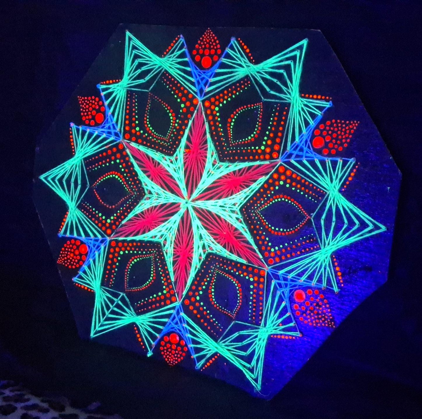 UV reactive geometric string art mandala “Blooming Anise” by Psybell glowing under blacklight, handmade dotted mandala wall art