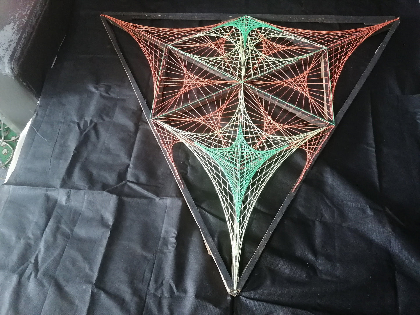 Geometric string art installation by Psybell displayed on a black background showing detailed thread pattern