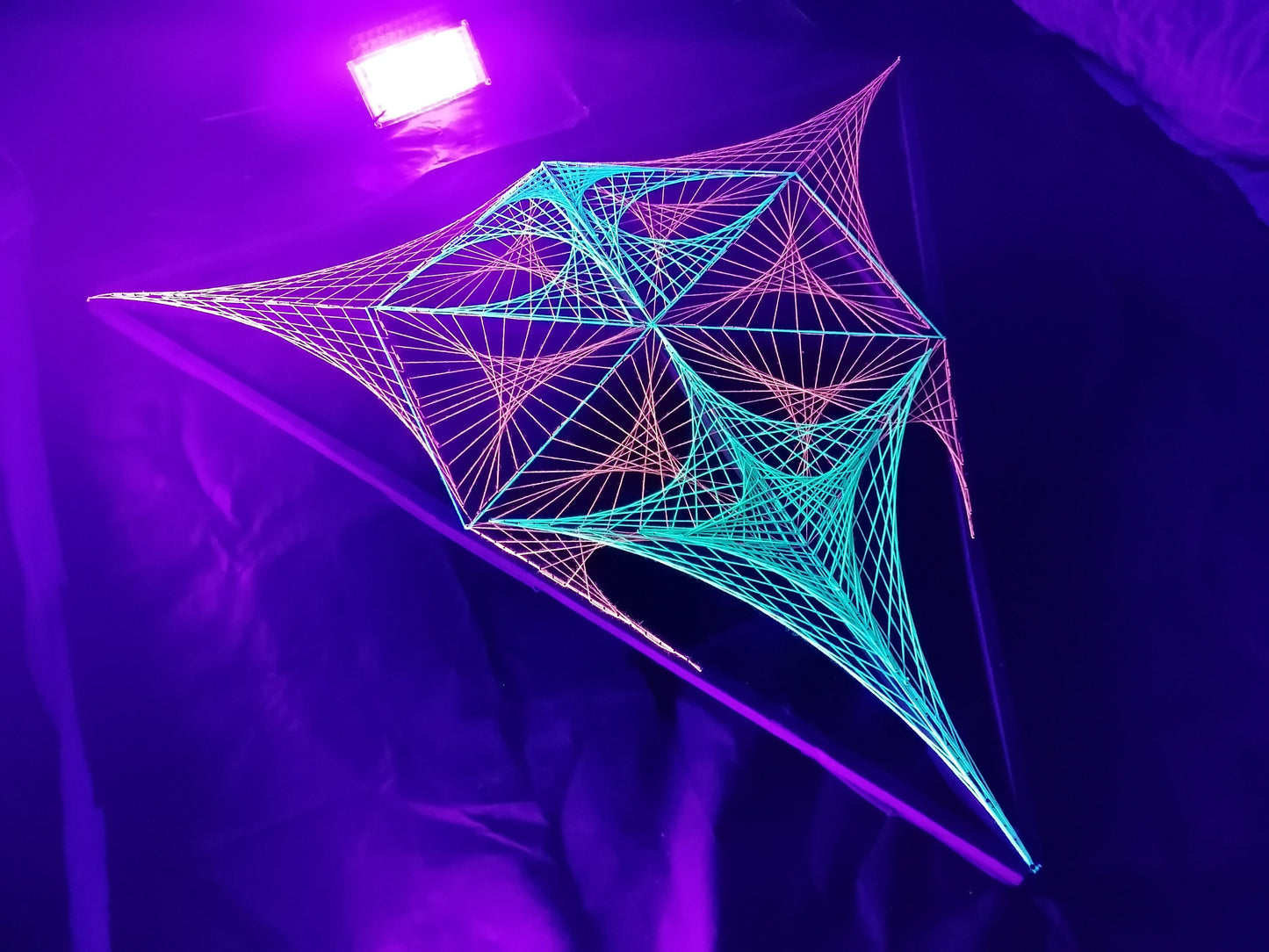 UV reactive geometric string art installation by Psybell glowing under purple UV lighting
