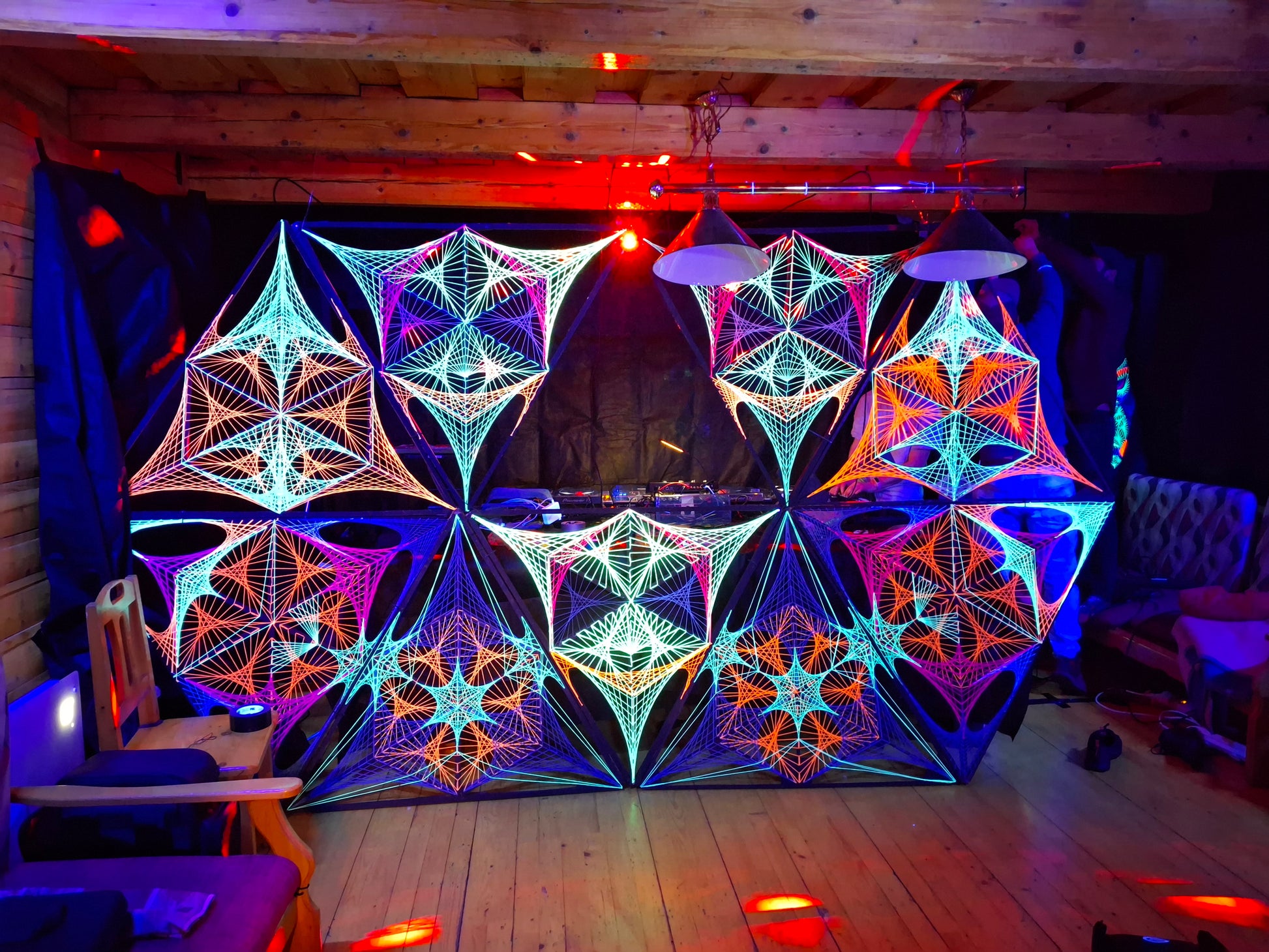 UV reactive geometric string art stage decoration by Psybell at rave cabin party in Slovakia, psychedelic installation glowing under blacklight