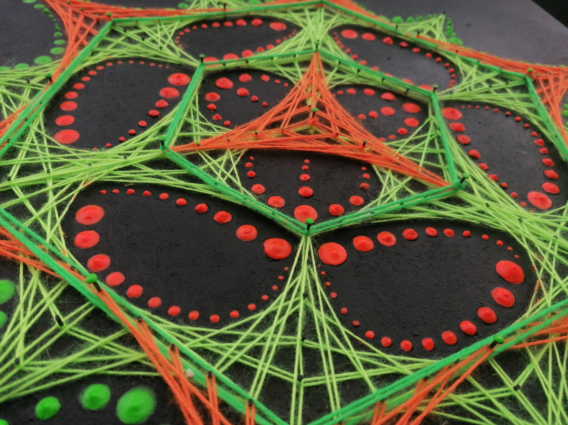 Macro detail of dotted mandala string art “Transformer” by Psybell showing colorful threads and red dot pattern