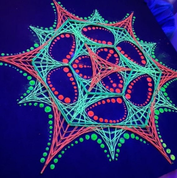 UV glow detail of dotted mandala string art “Transformer” by Psybell under blacklight on dark background