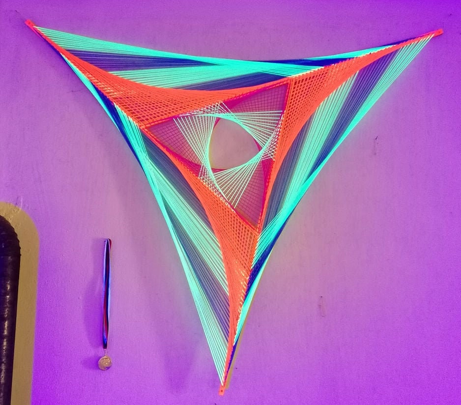 Geometric Windmill string art sculpture on wooden laths, UV reactive fiber art with layered triangular structure